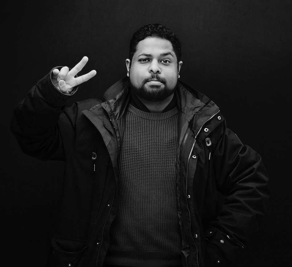 Portrait of photographer Shinu John holding a camera in his Dublin studio